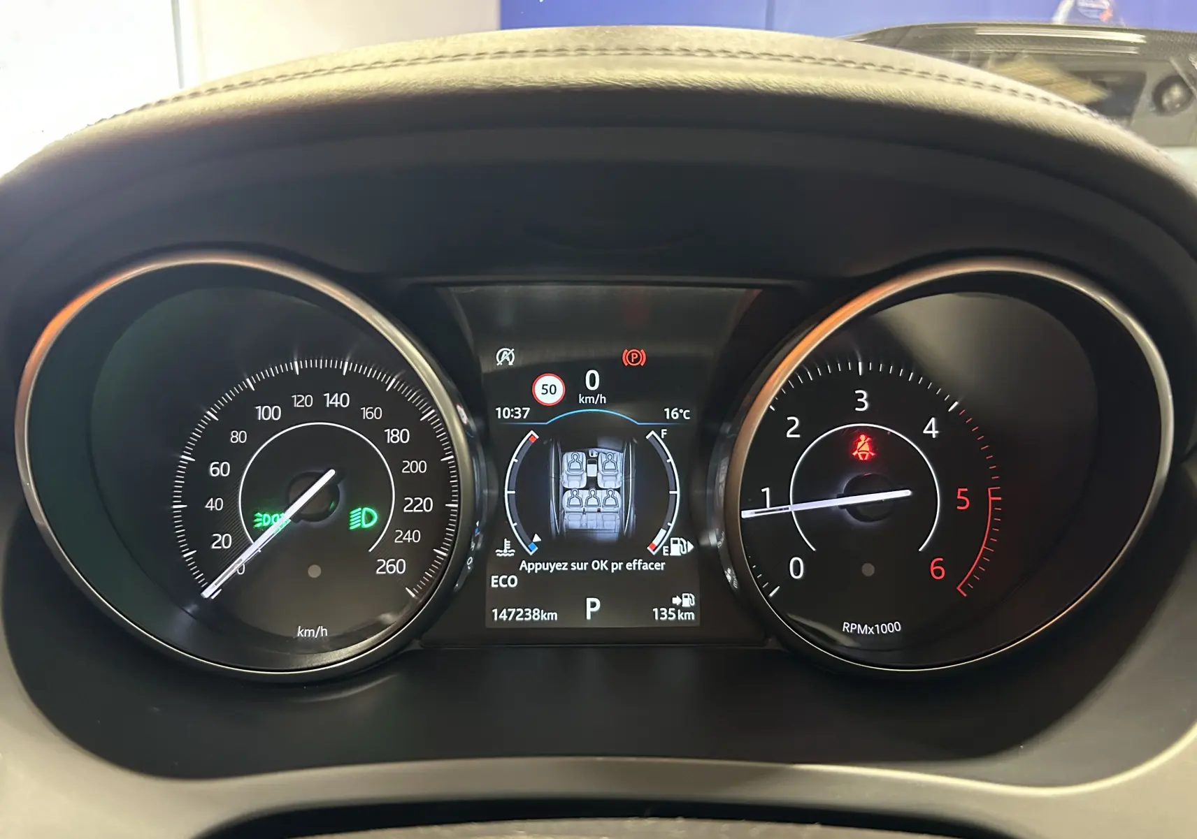 Tableau de bord de Jaguar E-Pace 2018 avec compteur de vitesse, compte-tours et écran central affichant la consommation et alertes.
