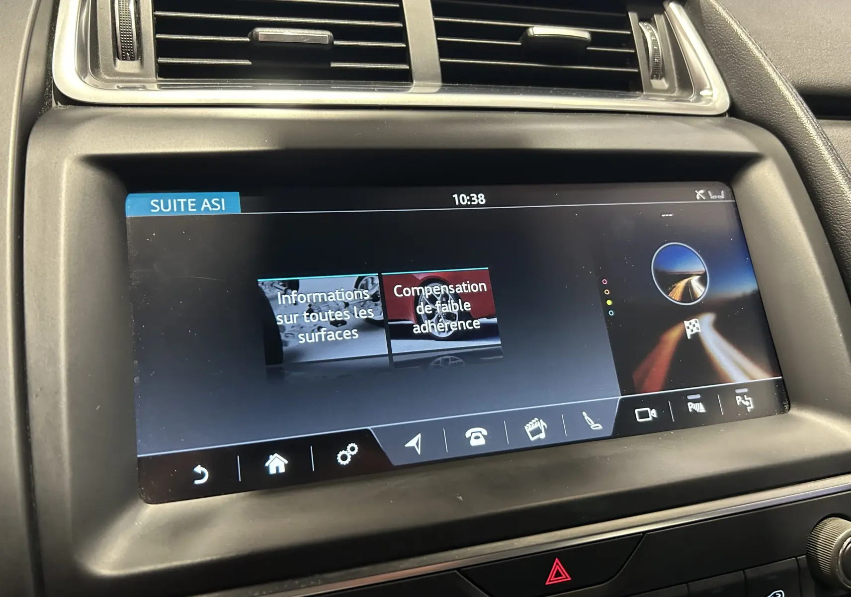 Gros plan sur l'écran tactile central du Jaguar E-PACE beige, affichant les options d'aide à la conduite.