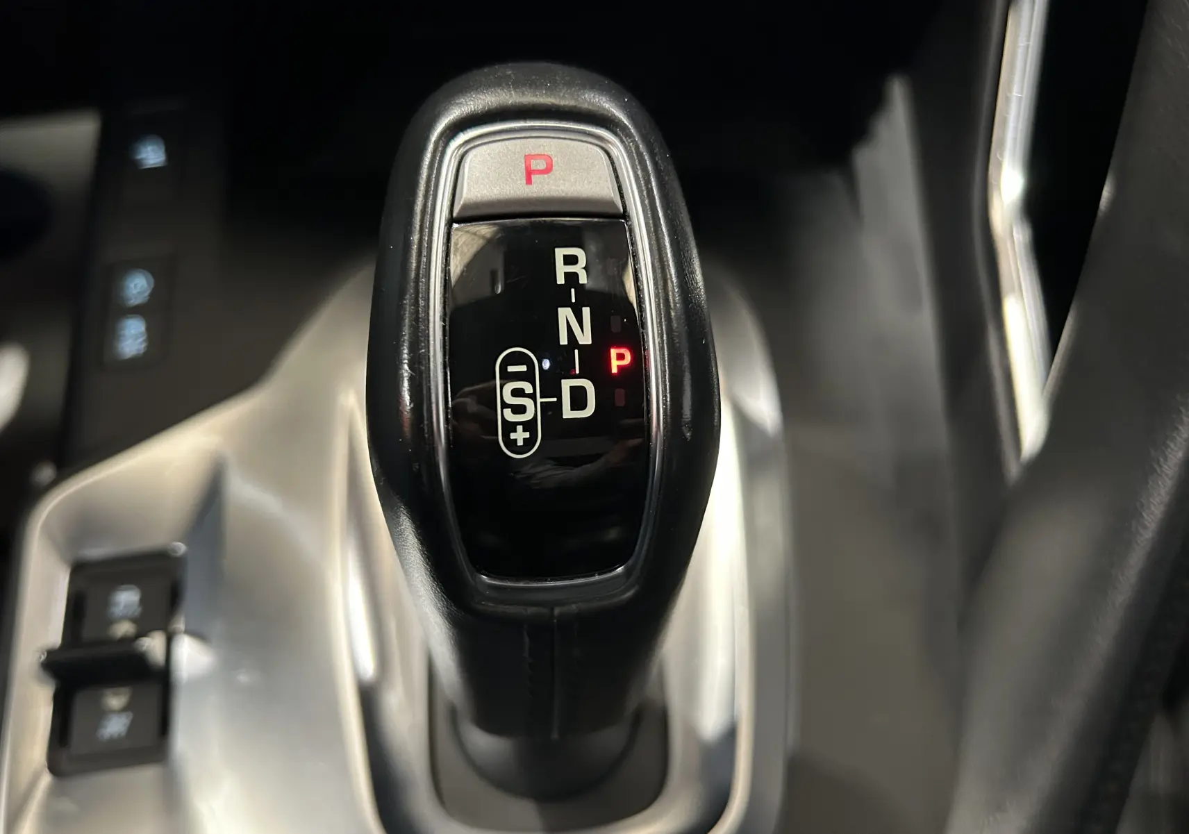 Le levier de vitesses noir de la Jaguar E-PACE 2018 en position parking, entouré de la console argentée.