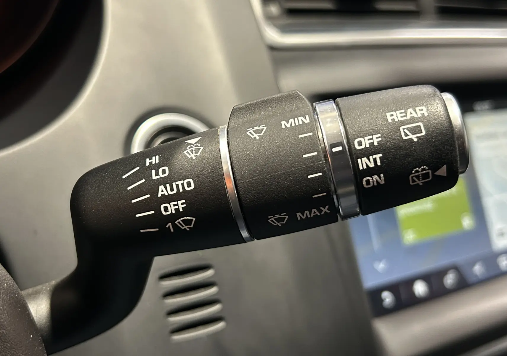 Gros plan sur la commande des essuie-glaces dans l’habitacle du Jaguar E-PACE beige, avec affichage des réglages visibles.