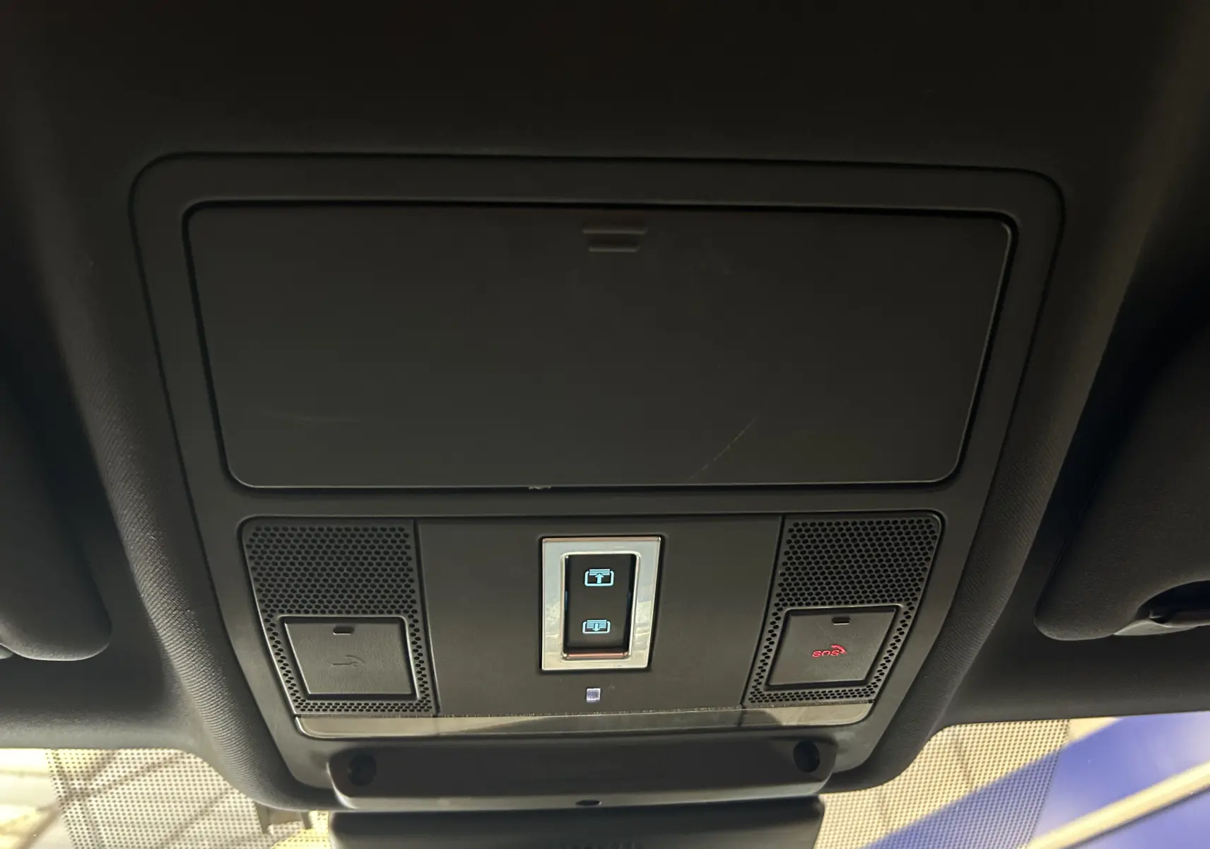 Vue en plongée sur le panneau de commande du toit panoramique et hayon électrique dans l'habitacle noir du Jaguar E-PACE beige.