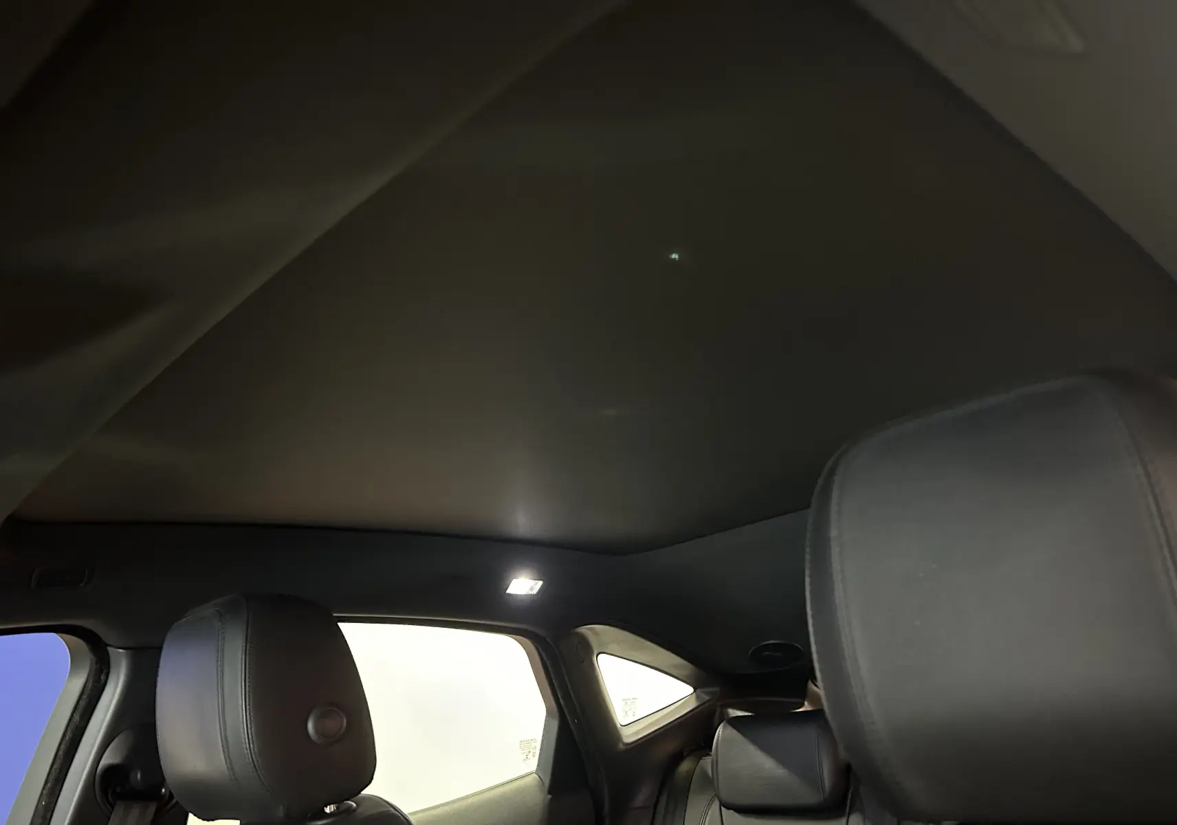 Vue intérieure arrière du Jaguar E-PACE 2018, montrant les sièges cuir noirs et le toit panoramique fermé.