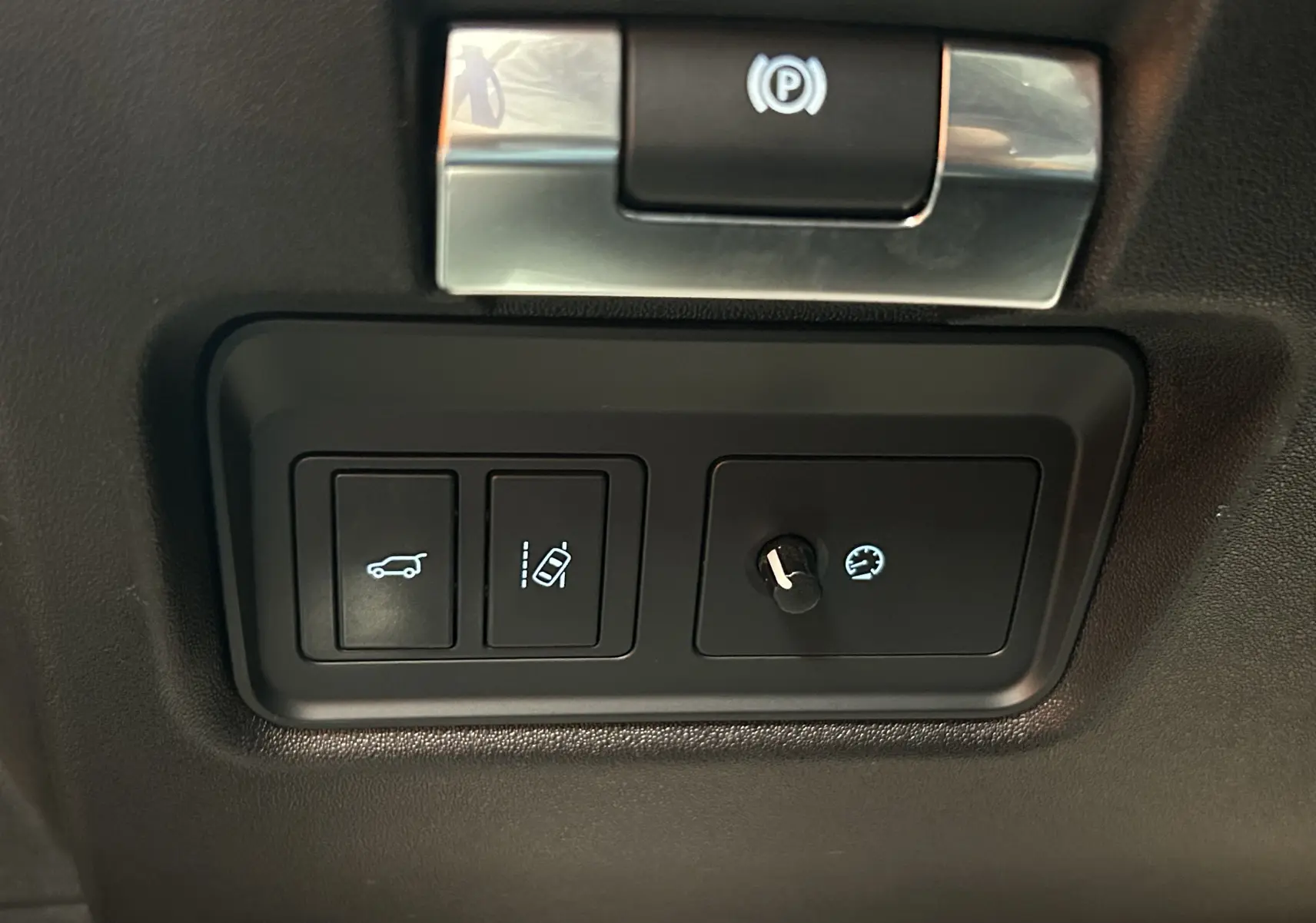 Gros plan sur les commandes intérieures noires du Jaguar E-PACE, incluant le bouton hayon électrique et régulateur de vitesse.