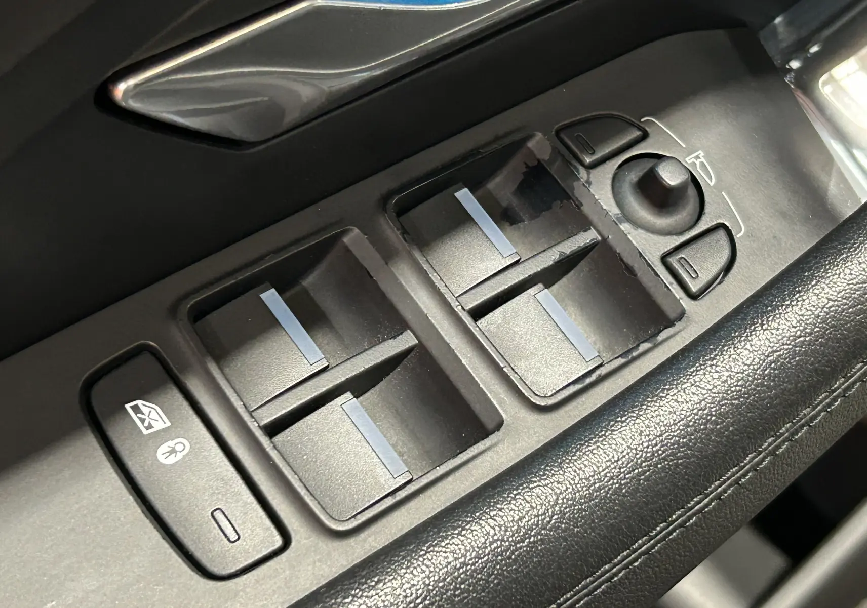 Gros plan sur les commandes de lève-vitres et rétroviseurs côté conducteur du Jaguar E-Pace beige de 2018.