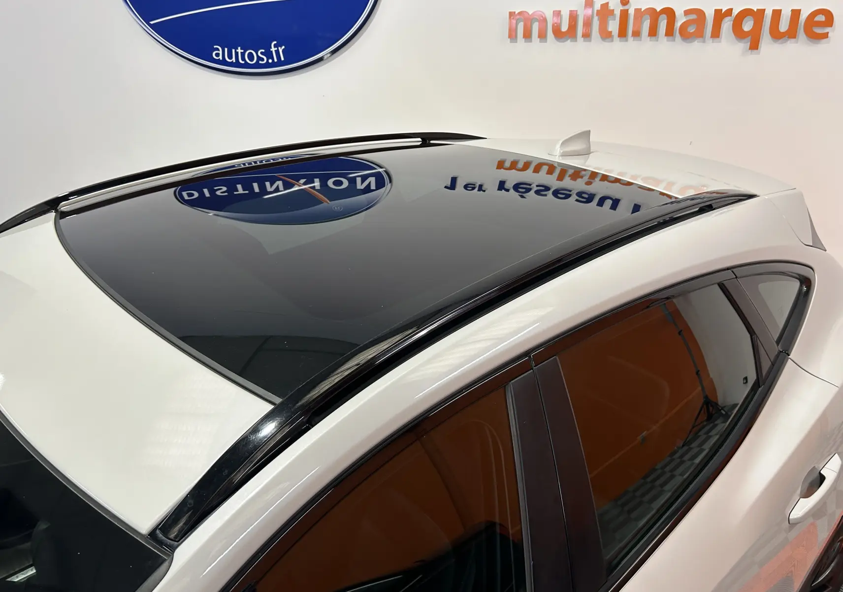 Vue en plongée du toit panoramique noir sur Jaguar E-PACE beige, avec vitrage latéral teinté et antenne requin.