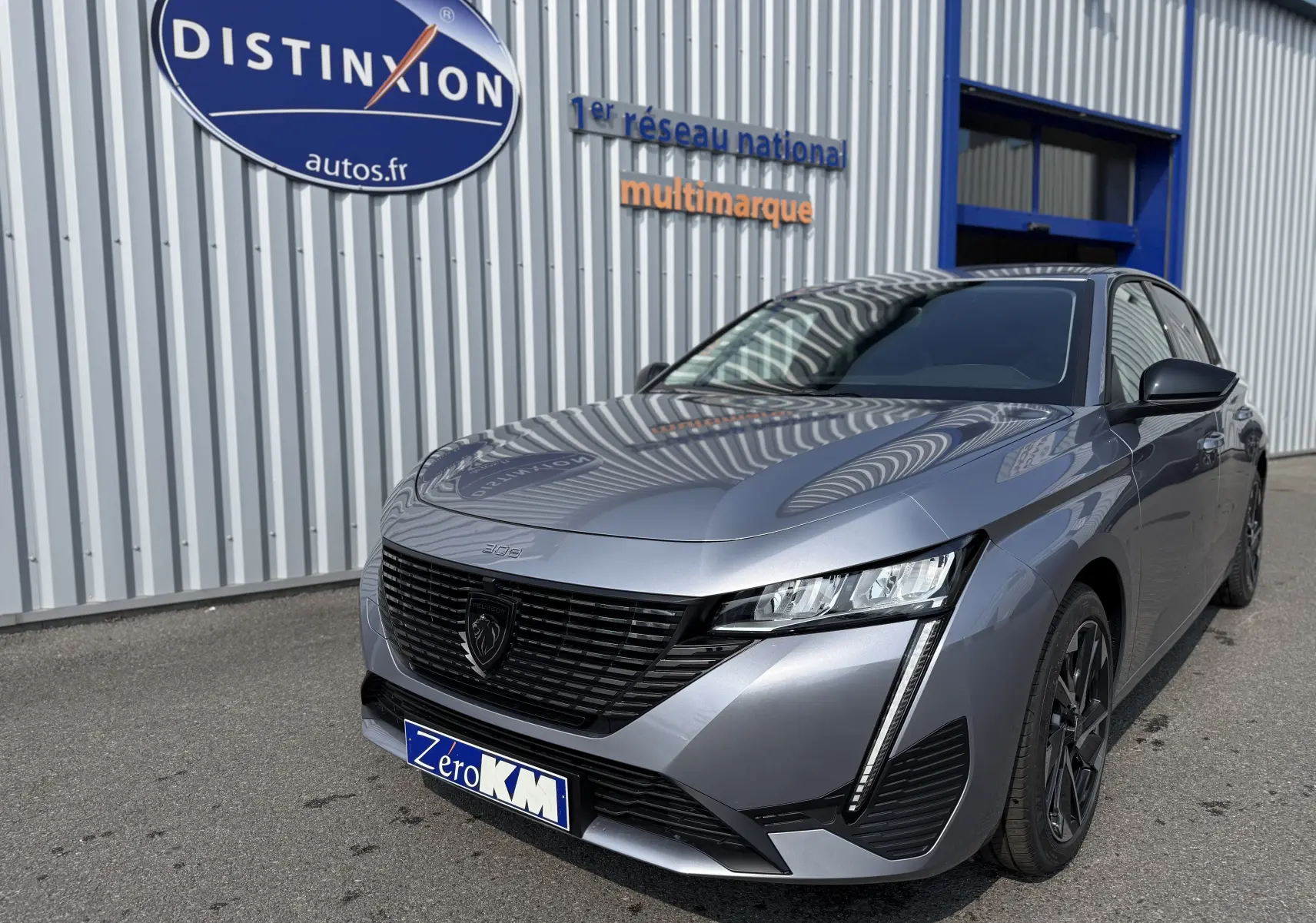 Peugeot 308 gris Artense vue 3/4 avant droit, avec calandre noire et feux LED verticaux distinctifs.