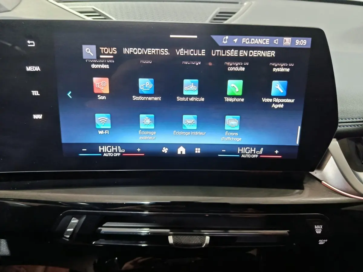 Écran tactile central du tableau de bord de la BMW X1 xDrive25e blanc, affichant le menu des réglages.