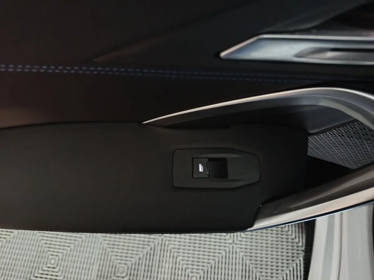 Gros plan sur la poignée intérieure noire de la porte côté gauche d’un BMW X1 blanc 2024.