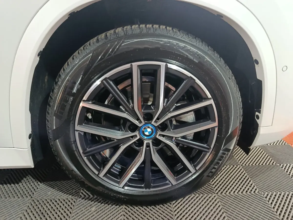 Gros plan sur la roue avant droite noire et argentée du BMW X1 blanc xDrive25e M Sport 2024.