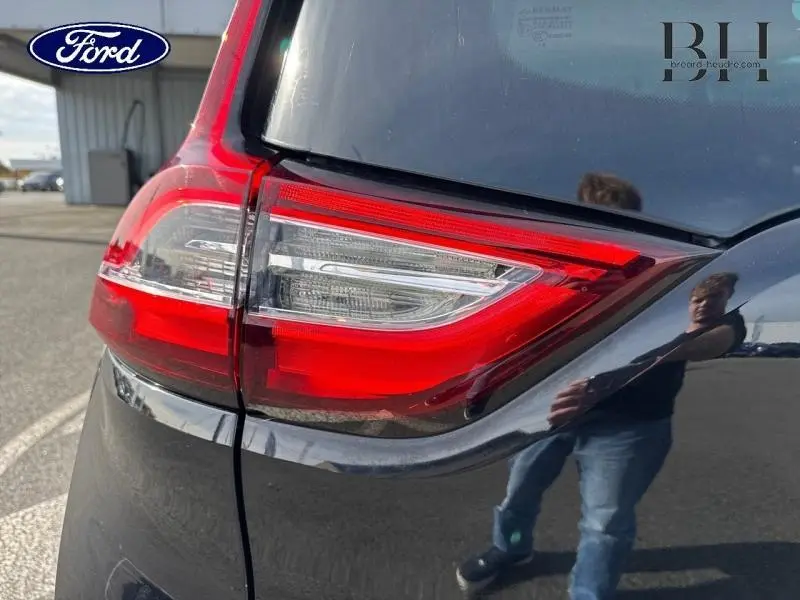 Gros plan sur le feu arrière droit d’un Renault Grand Scénic noir étoilé, avec reflet sur la carrosserie.