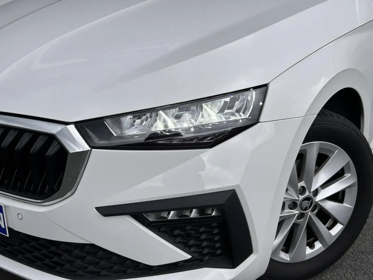 Gros plan sur l'avant droit blanc Candy d'une Skoda Scala 2025, mettant en valeur le phare Full LED et la jante alliage 16 pouces.