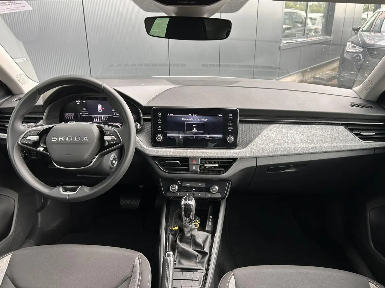 Vue intérieure avant du Skoda Scala blanc Candy 2025, volant cuir multifonctions et écran tactile central visible.