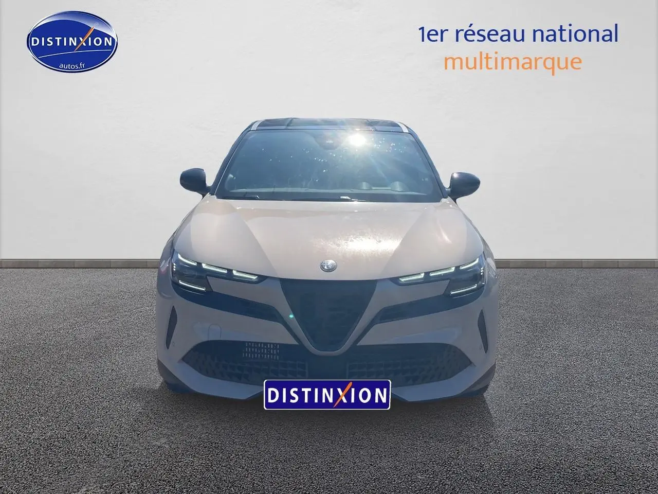 Vue frontale d'une Alfa Romeo Junior 1.2 hybride 2026 ivoire et noir avec phares matrix LED allumés.