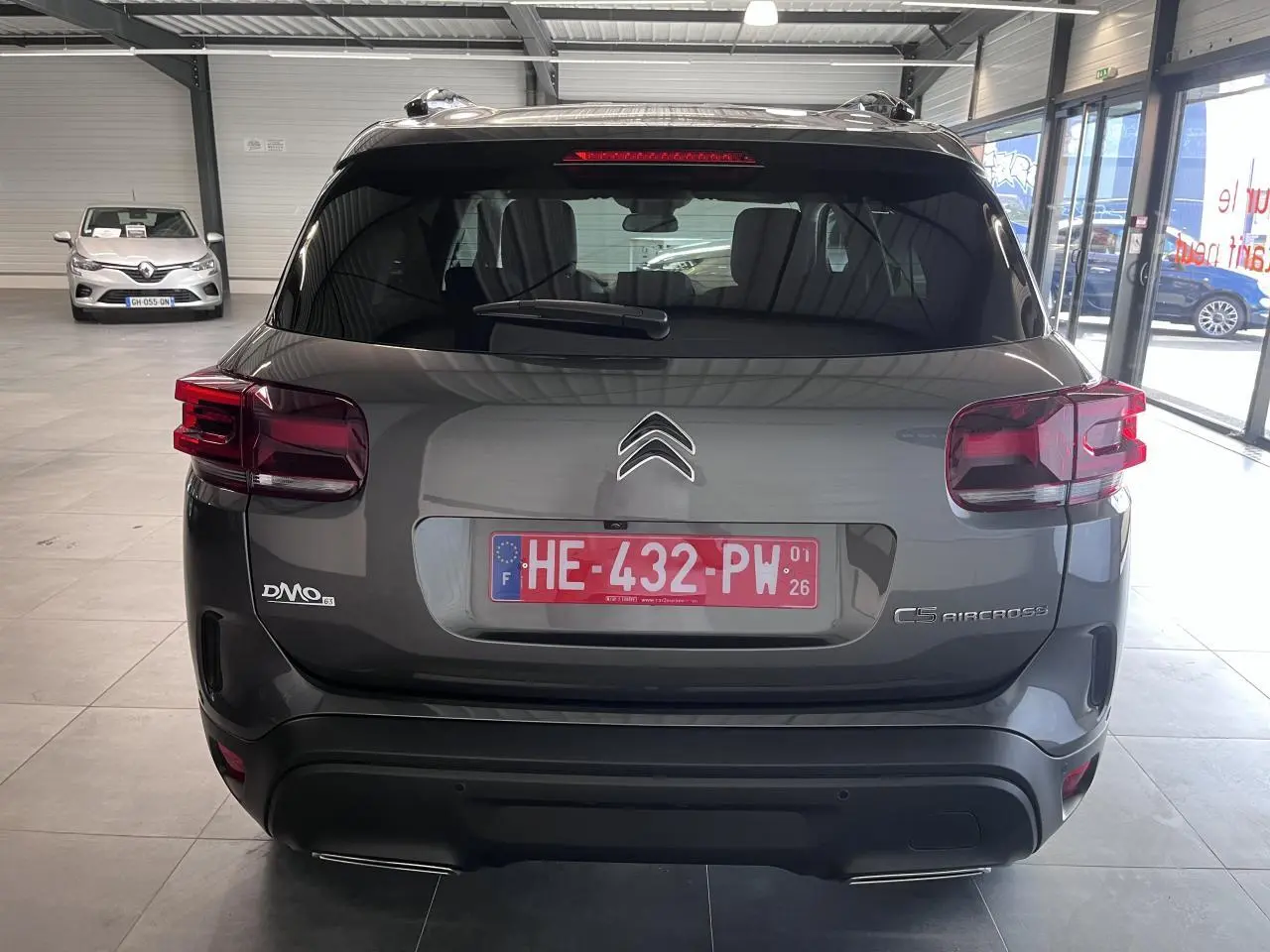 Vue arrière d'un Citroën C5 Aircross gris platinium en showroom, avec feux arrière LED et double sortie d'échappement.