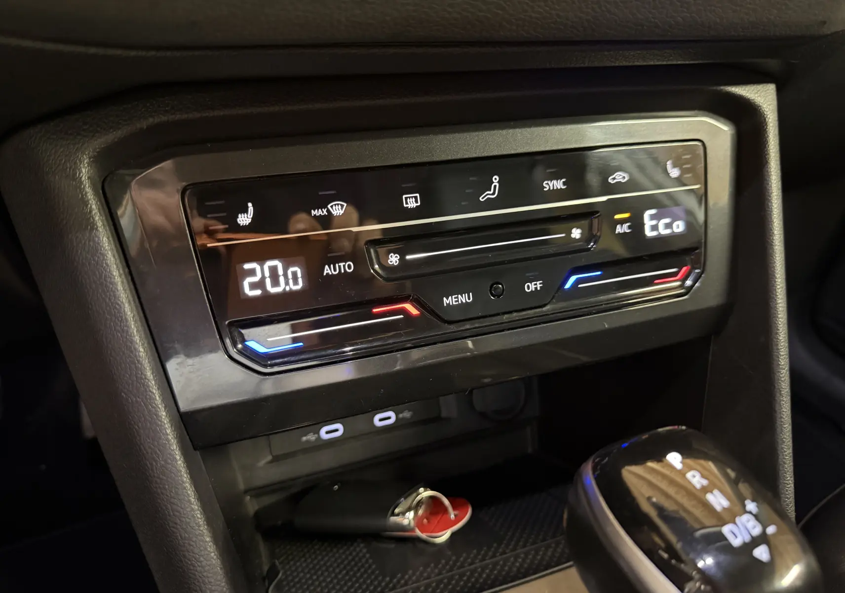 Gros plan sur la console centrale noire du Volkswagen Tiguan 2022, affichant la climatisation digitale et le levier de vitesse automatique.