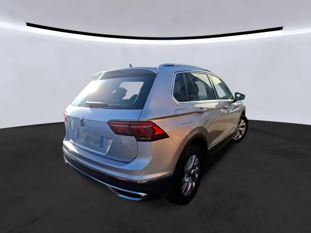 Vue 3/4 arrière droite d'un Volkswagen Tiguan gris clair 2022 hybride rechargeable avec feux arrière LED et toit ouvrant.