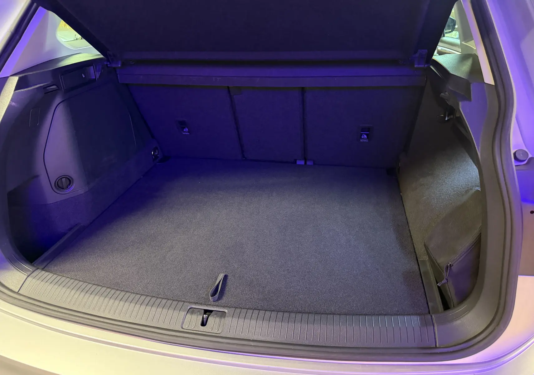 Coffre ouvert vu de l'arrière d'un Volkswagen Tiguan gris clair, montrant un espace de chargement propre et spacieux.