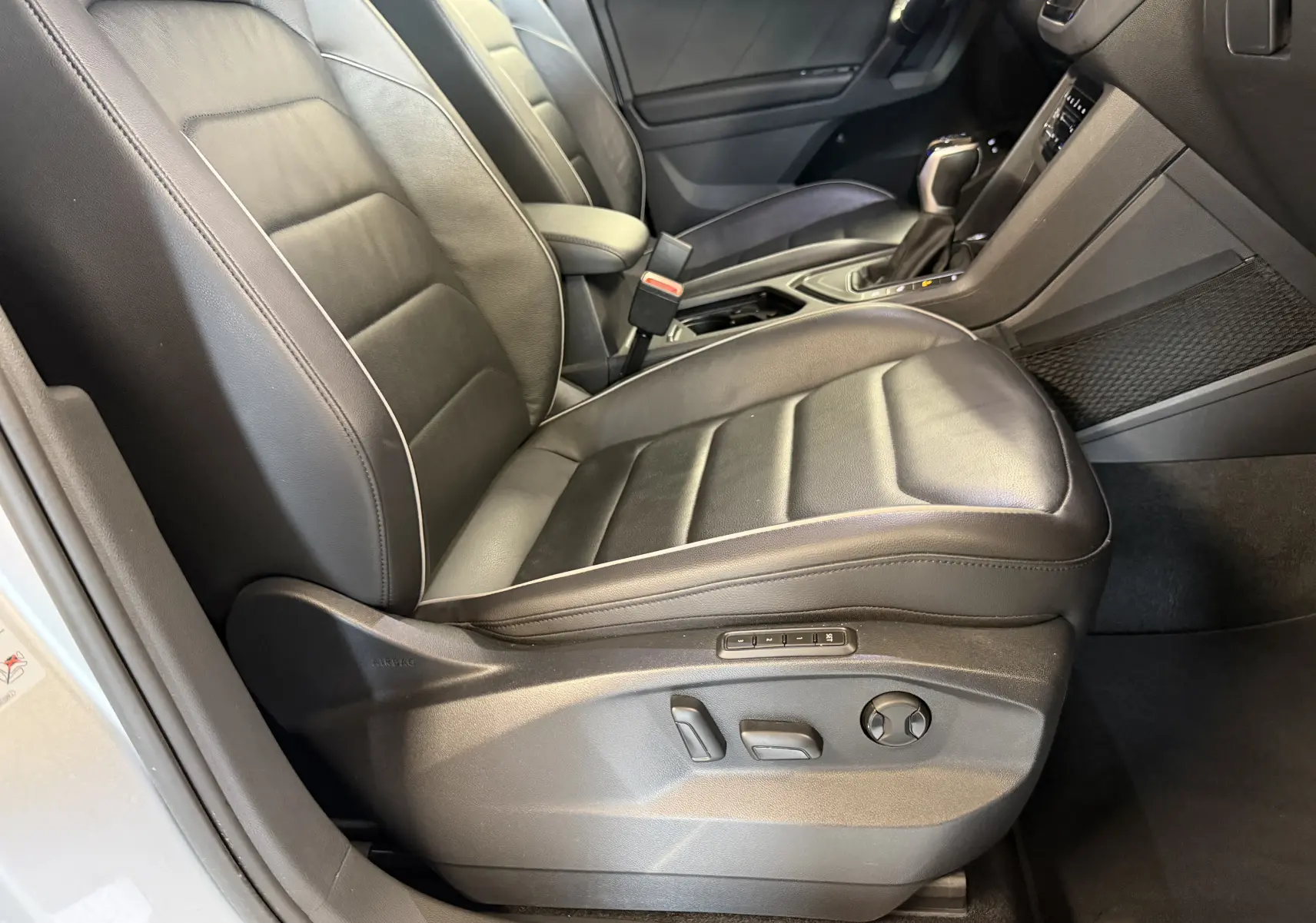 Vue intérieure côté conducteur du Volkswagen Tiguan 1.4 e-Hybrid 2022, sièges en cuir noir avec réglages électriques.
