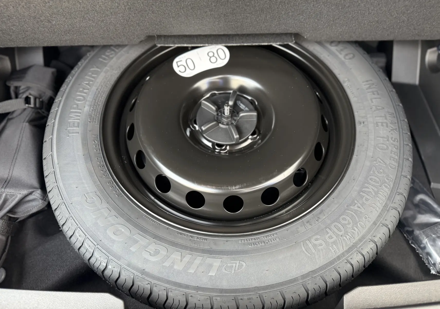 Gros plan sur la roue de secours noire dans le coffre du Renault Austral 2025 hybride bleu Iron toit noir.