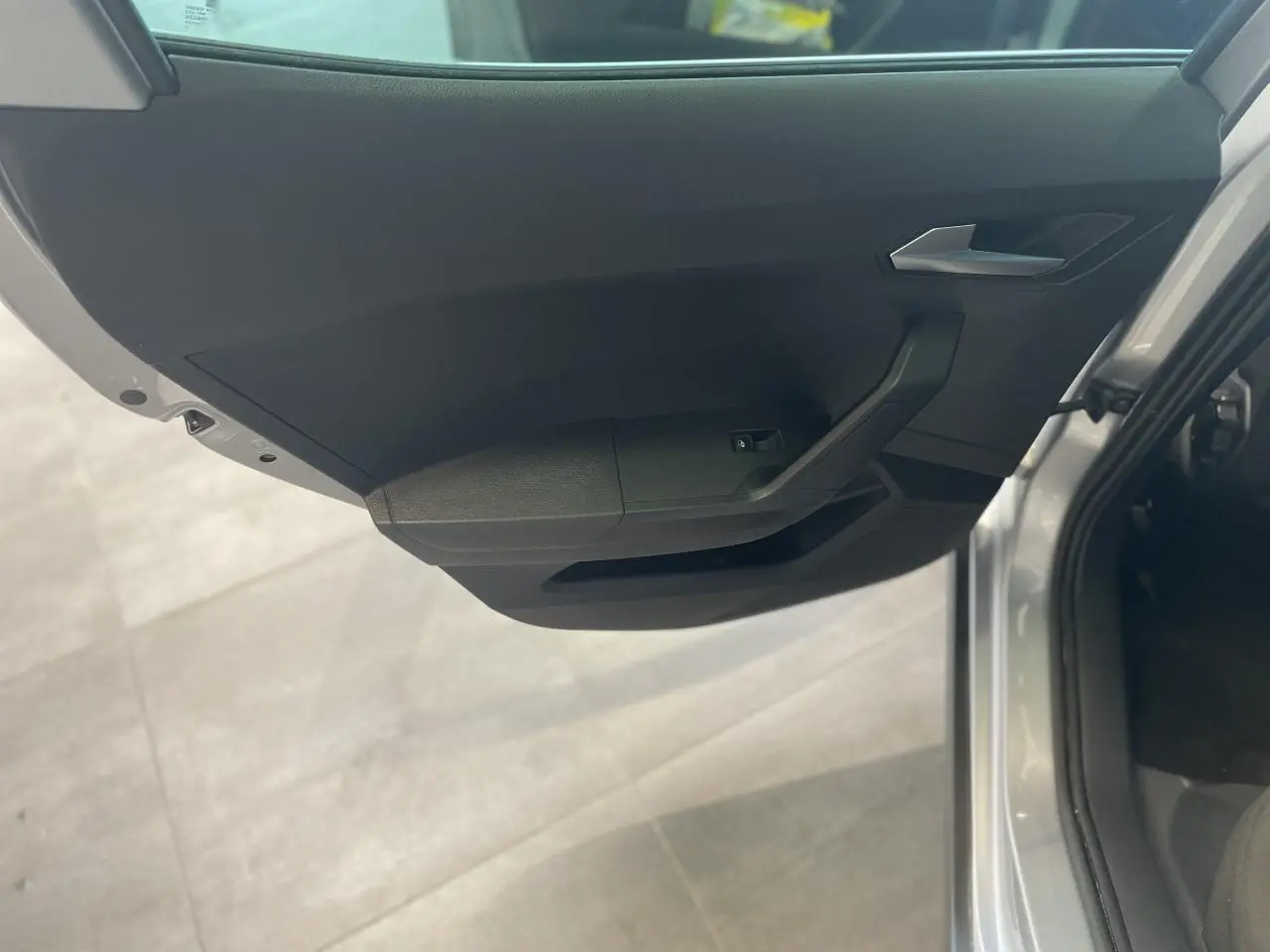 Vue rapprochée de la porte avant gauche noire du SEAT ARONA 2024, avec poignée argentée et bouton de lève-vitre.