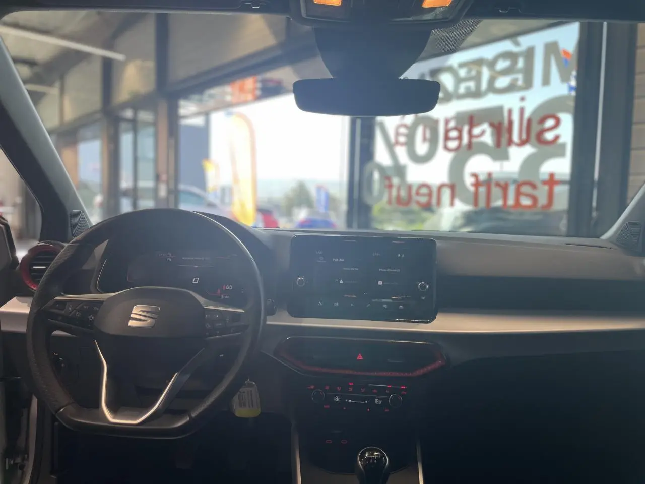 Vue intérieure avant du tableau de bord de la SEAT Arona 2024 avec volant sport cuir et écran tactile 8,25 pouces.