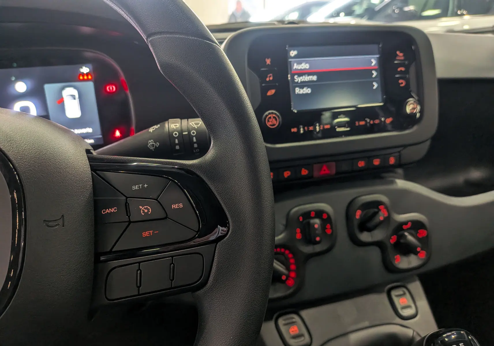 Vue rapprochée du tableau de bord et volant noir de la Fiat Panda 1.0 Hybrid 2025 avec commandes au volant et écran tactile.