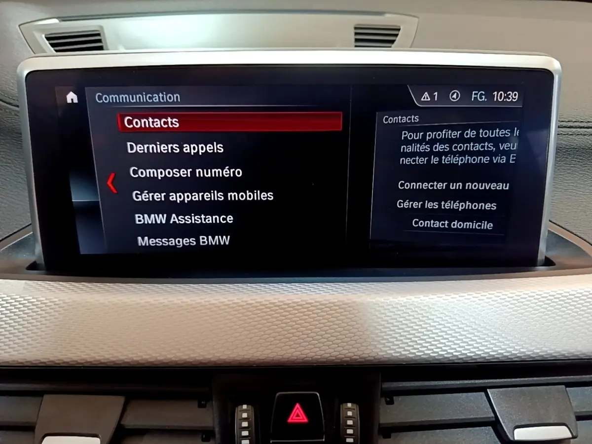 Écran tactile central 8,8 pouces affichant le menu communication dans l’habitacle d’une BMW X1 blanche.