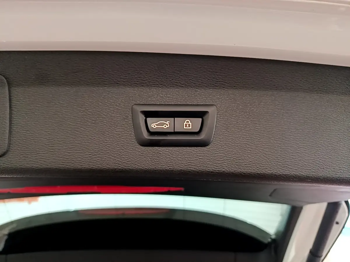 Gros plan sur les boutons d’ouverture et de verrouillage électrique du coffre du BMW X1 blanc, vue intérieure du hayon.