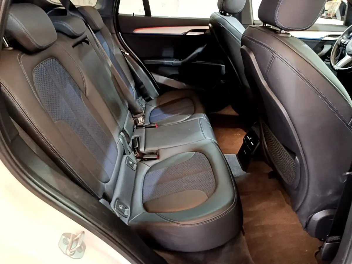 Vue intérieure côté gauche des sièges arrière en cuir noir et tissu bleu du BMW X1 sDrive18i M Sport 2022.