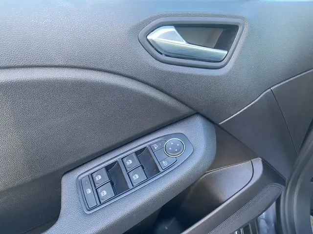 Gros plan sur la porte avant gauche de la Renault Clio V gris schiste, montrant les commandes des vitres électriques et le bouton de réglage des rétroviseurs.