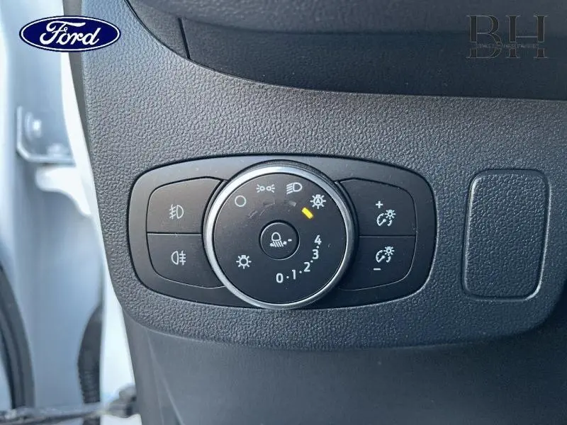 Gros plan sur le bouton de réglage des phares dans l'habitacle du Ford Puma blanc, côté gauche conducteur.