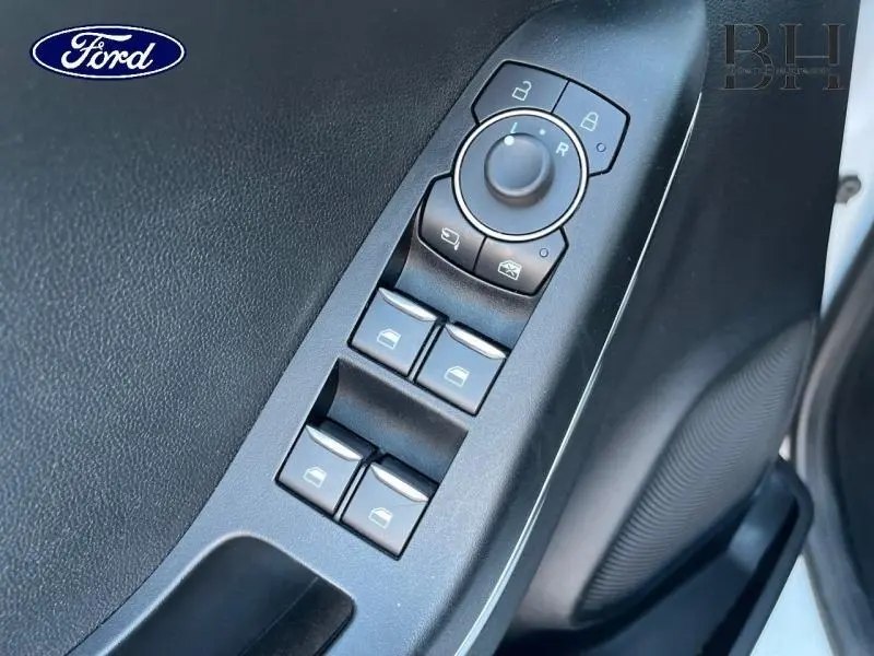 Gros plan sur les commandes de lève-vitres et rétroviseurs côté conducteur du Ford Puma blanc, intérieur noir.