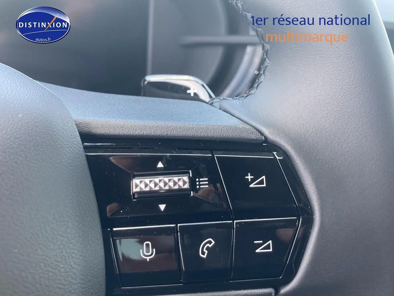 Gros plan sur les commandes multifonctions noires au volant de l'Alfa Romeo Junior gris, avec molette et boutons tactiles.