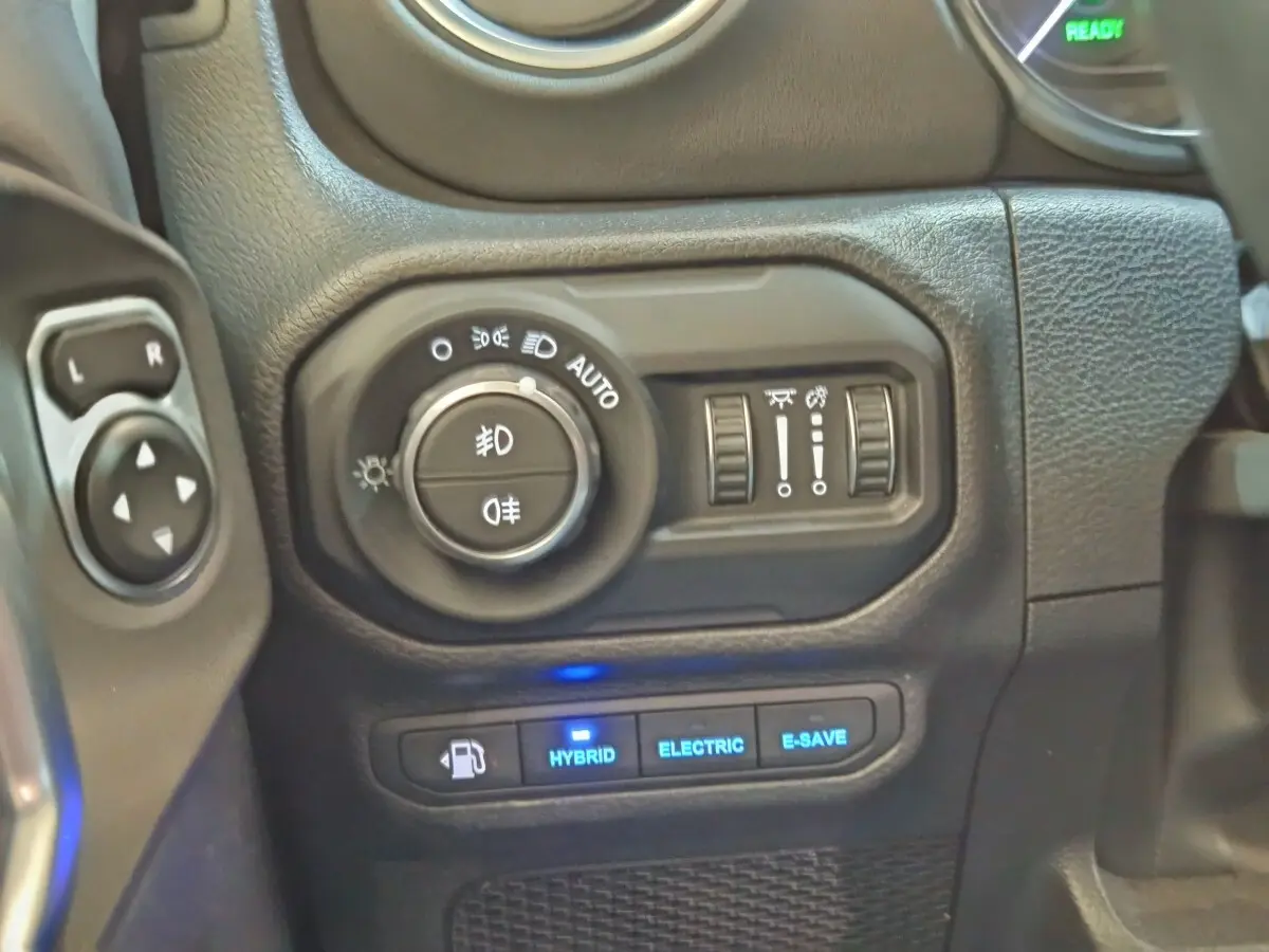 Gros plan sur les commandes d’éclairage et modes hybride du tableau de bord d’une Jeep Wrangler 2022.