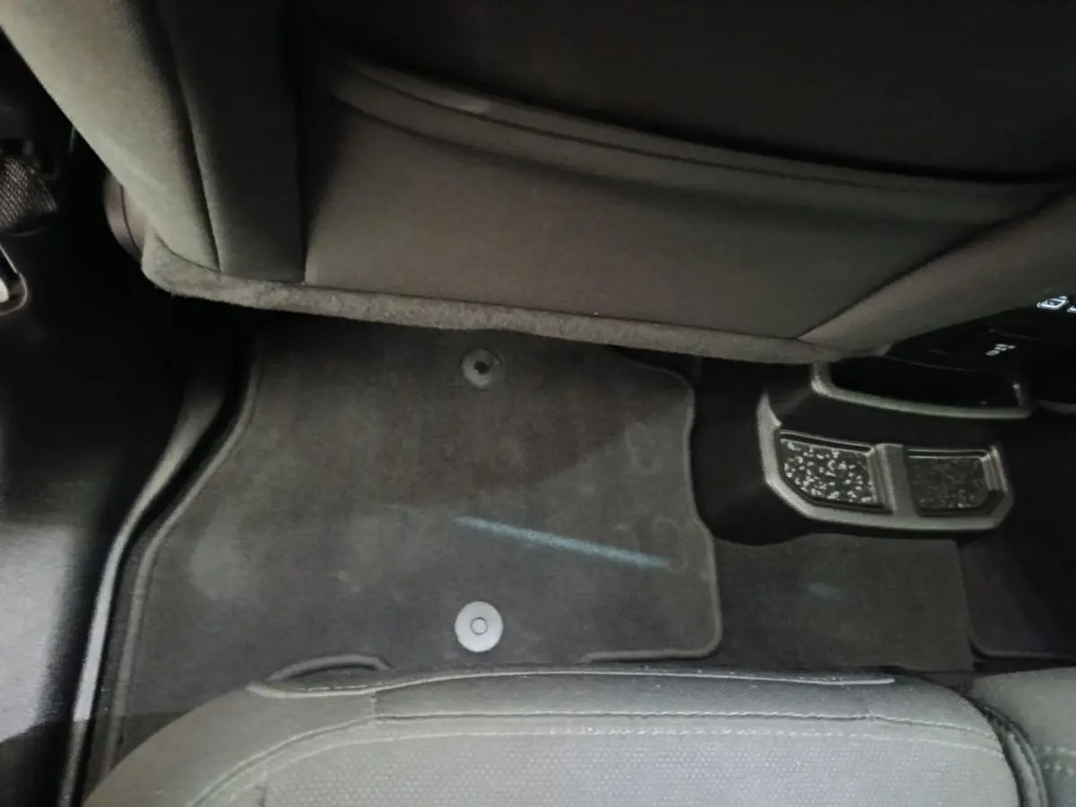 Vue intérieure du plancher arrière gris foncé de la Jeep Wrangler 2022 avec tapis de sol et partie inférieure des sièges noirs.