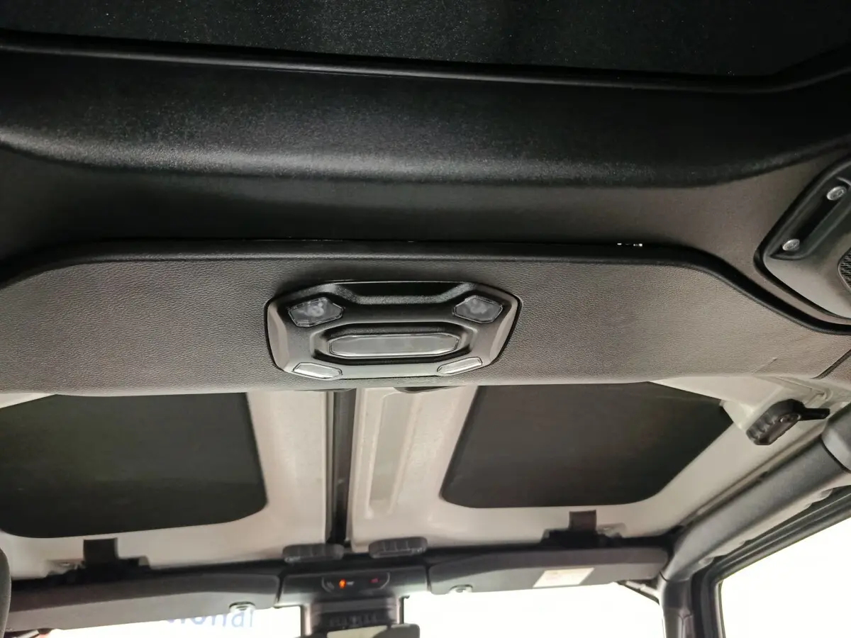 Vue intérieure du toit cabriolet gris foncé du Jeep Wrangler 2022 avec commandes d'éclairage intégrées au plafond.