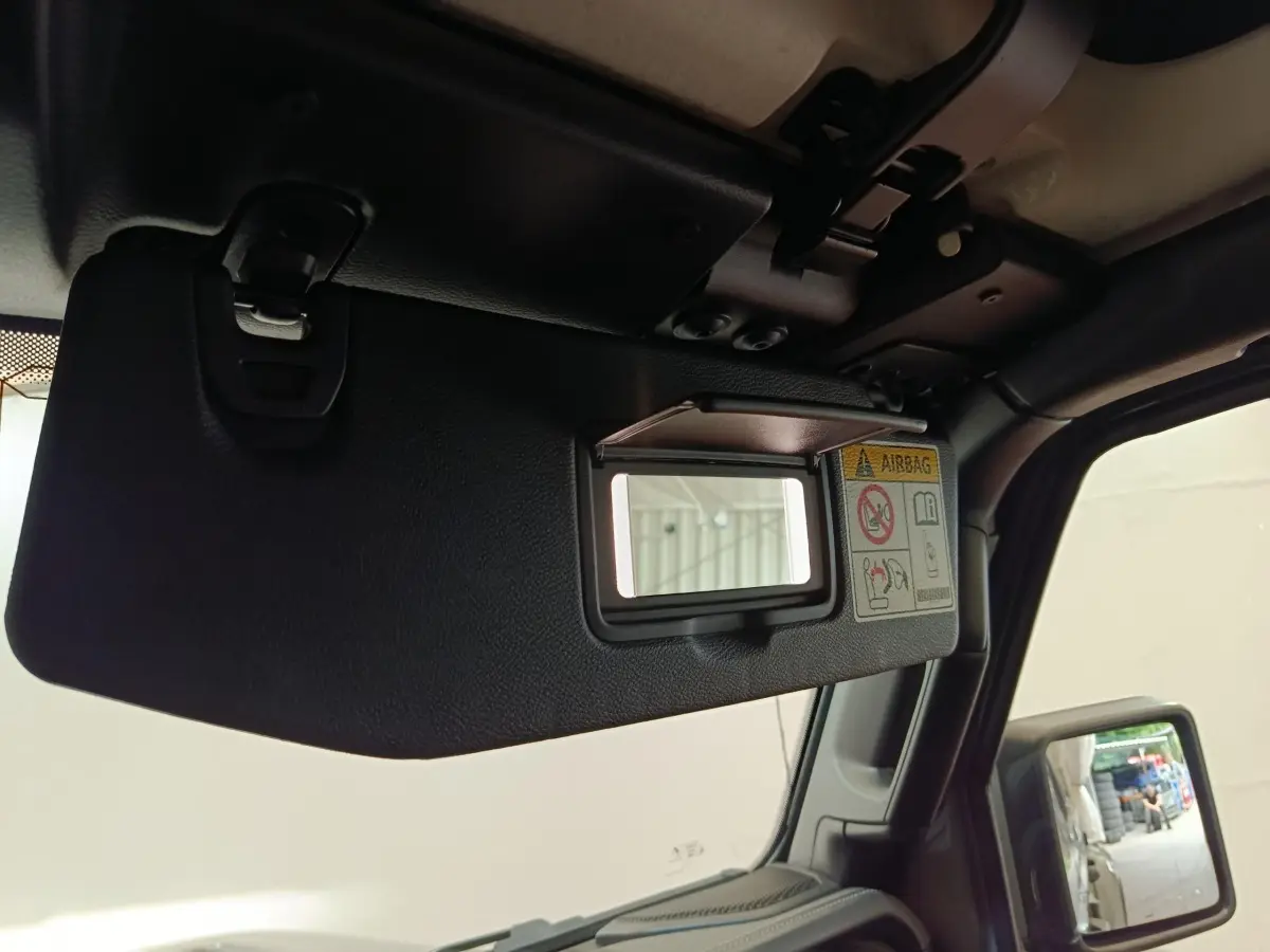 Détail du pare-soleil côté conducteur avec miroir intégré et étiquette airbag dans l’habitacle du Jeep Wrangler gris foncé.