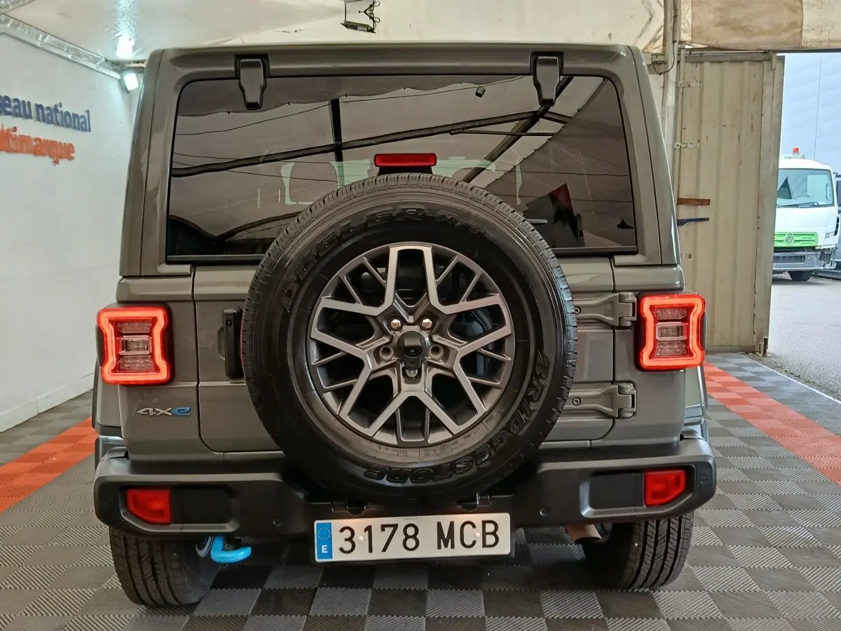 Vue arrière d'un Jeep Wrangler gris foncé avec roue de secours centrale et feux arrière LED en forme de C.