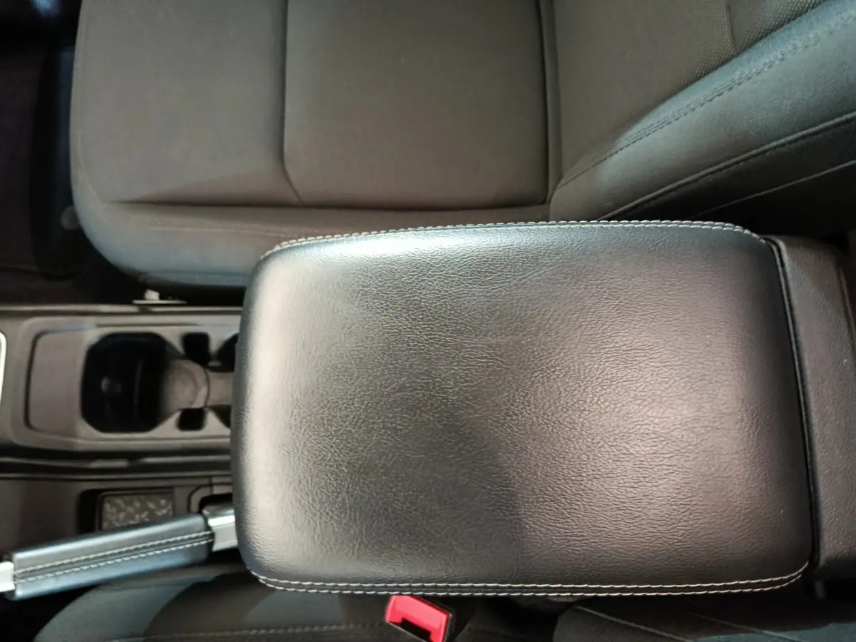 Vue rapprochée de l'accoudoir en cuir noir et siège tissu gris foncé à l'intérieur d'un Jeep Wrangler 2022.