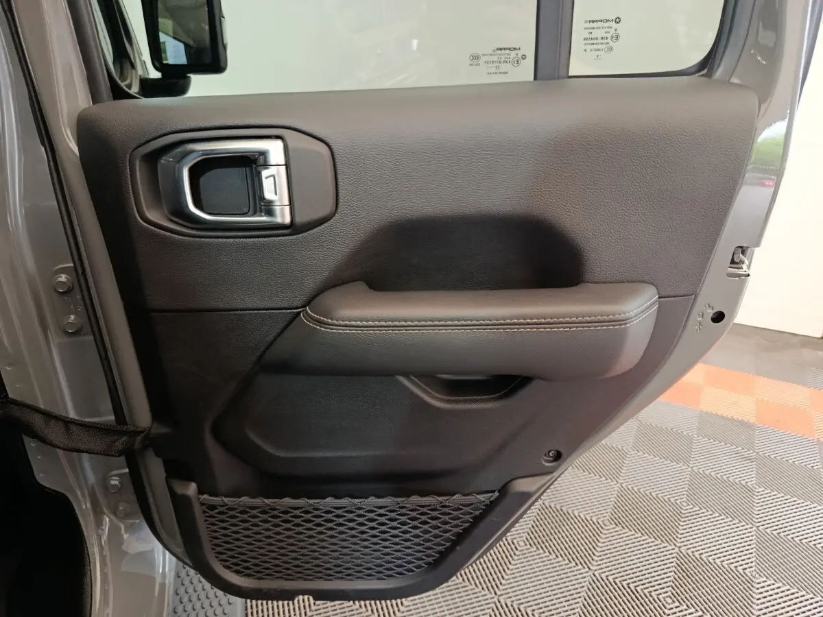 Vue rapprochée de la porte arrière droite gris foncé du Jeep Wrangler 2022, avec poignée intérieure et filet de rangement.