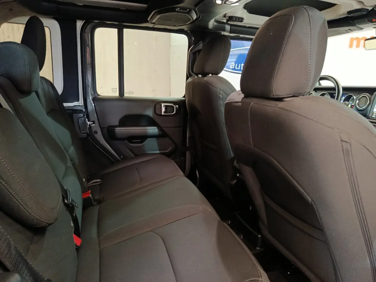 Vue intérieure arrière côté gauche du Jeep Wrangler 2022, sièges tissu gris foncé et espace arrière visible.
