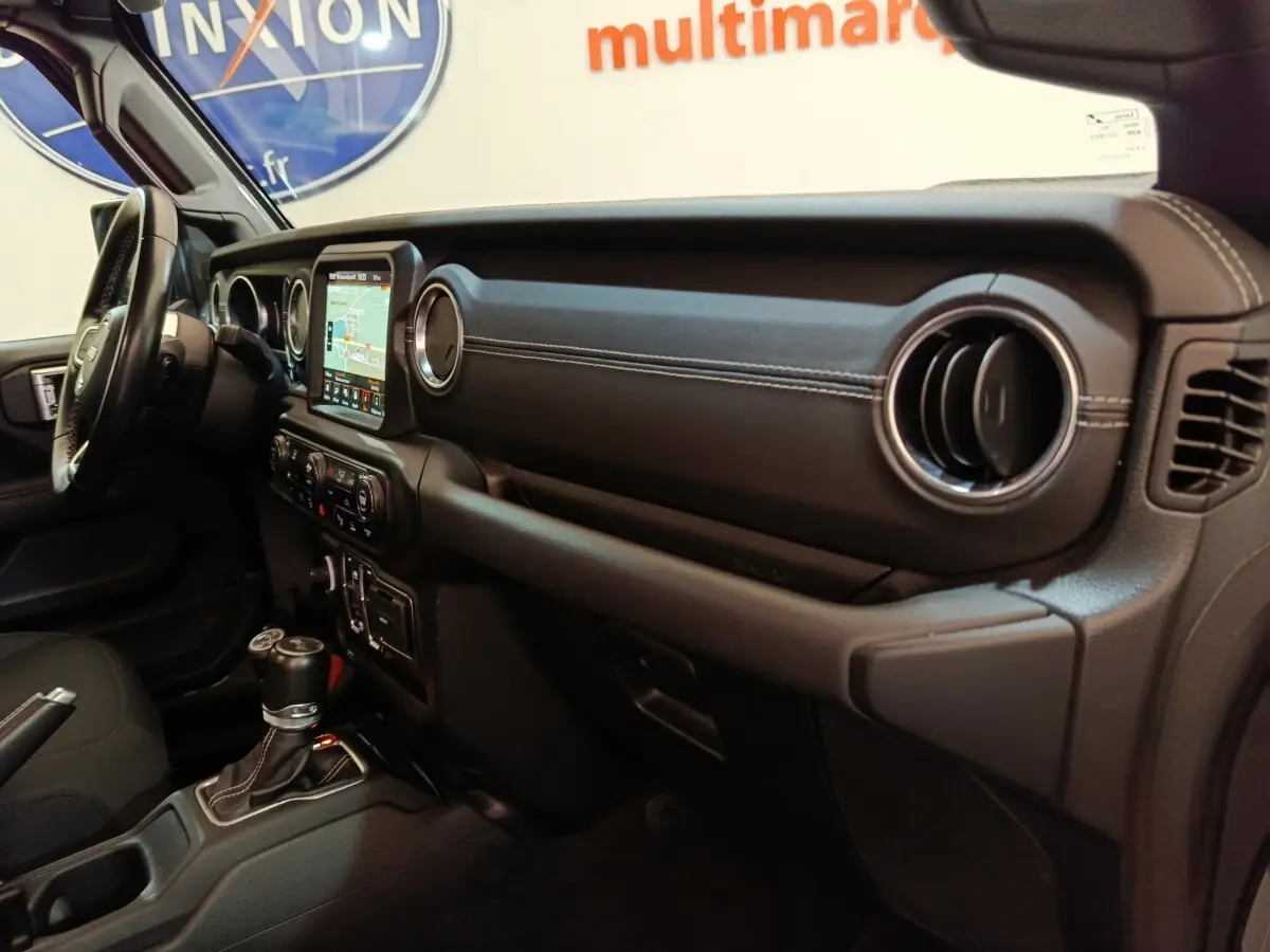 Vue intérieure côté passager du tableau de bord noir avec écran tactile et volant cuir de la Jeep Wrangler 2022.