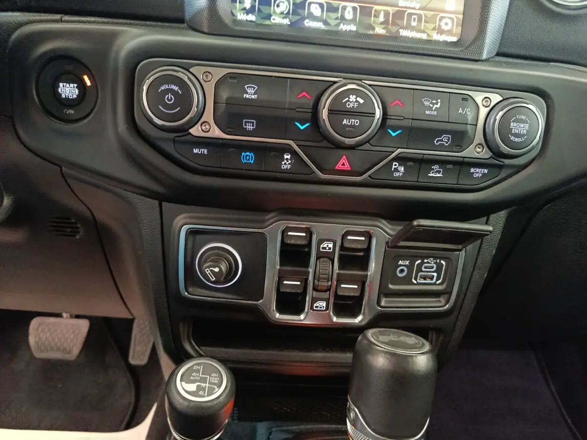 Vue rapprochée du tableau de bord central et console de la Jeep Wrangler 2022, avec commandes climatisation et leviers 4x4.