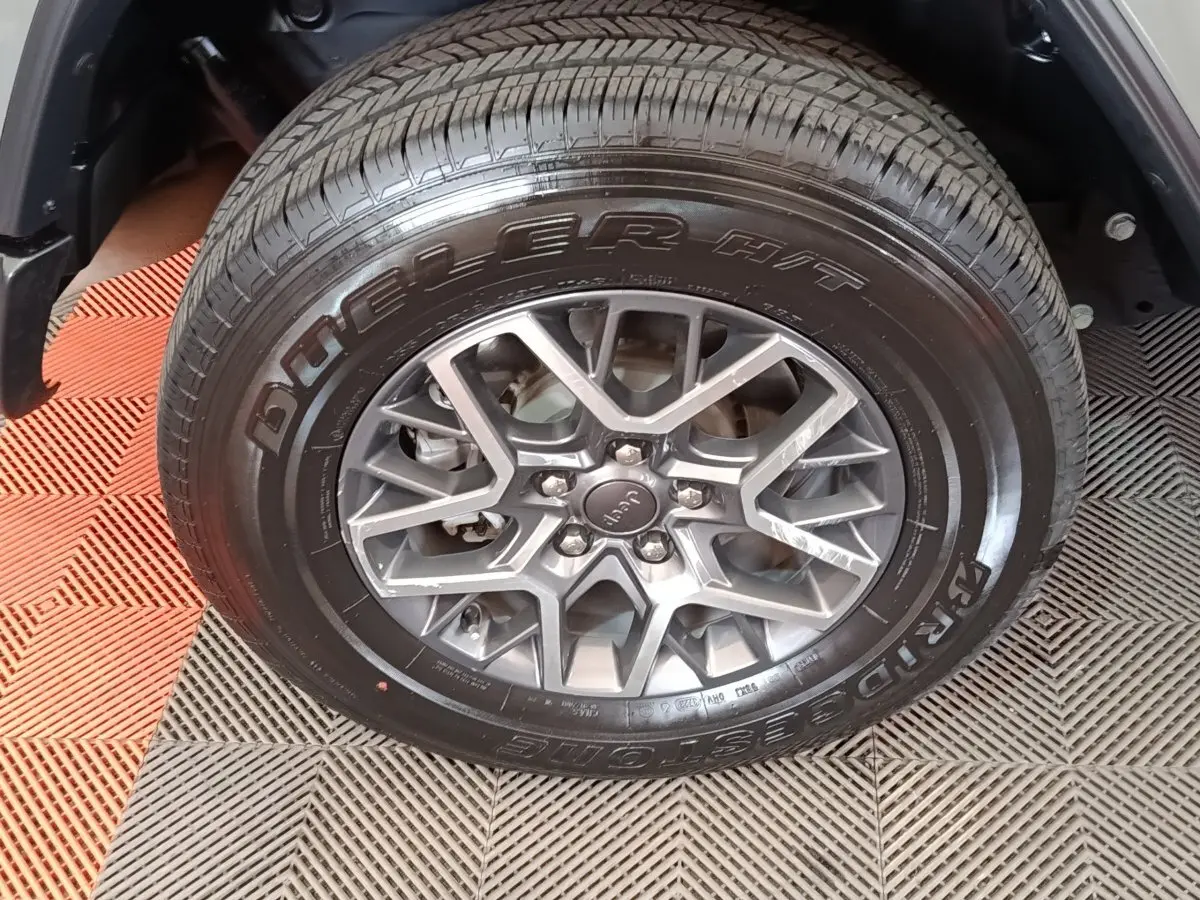 Gros plan sur la roue avant droite gris foncé d’un Jeep Wrangler 2022 avec jante alliage et pneu Bridgestone Dueler.
