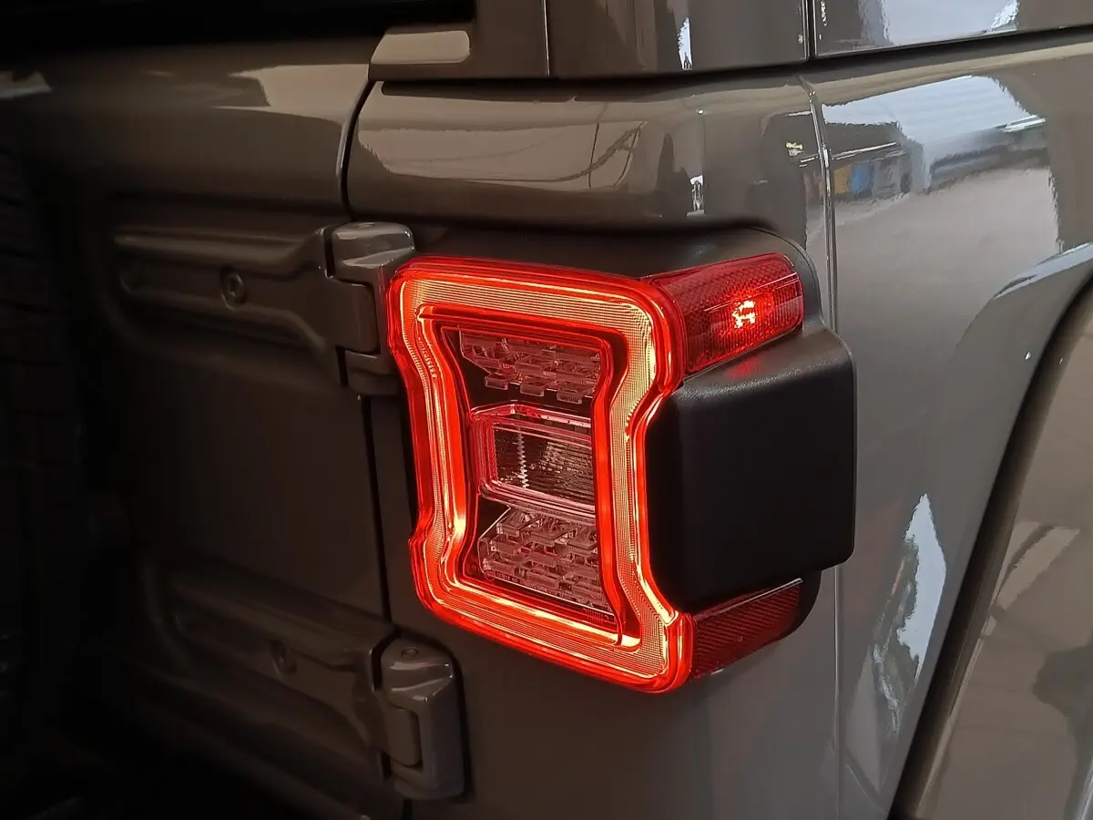 Gros plan sur le feu arrière droit rouge d’un Jeep Wrangler gris foncé 2022, avec charnières visibles sur la porte arrière.