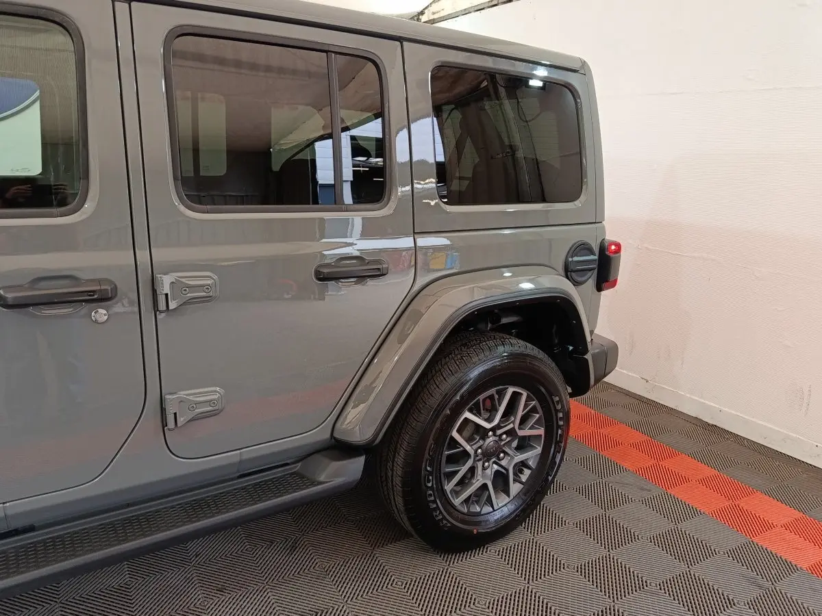 Vue latérale droite sur l’arrière d’un Jeep Wrangler 2022 gris foncé avec jante aluminium et porte essence visible.