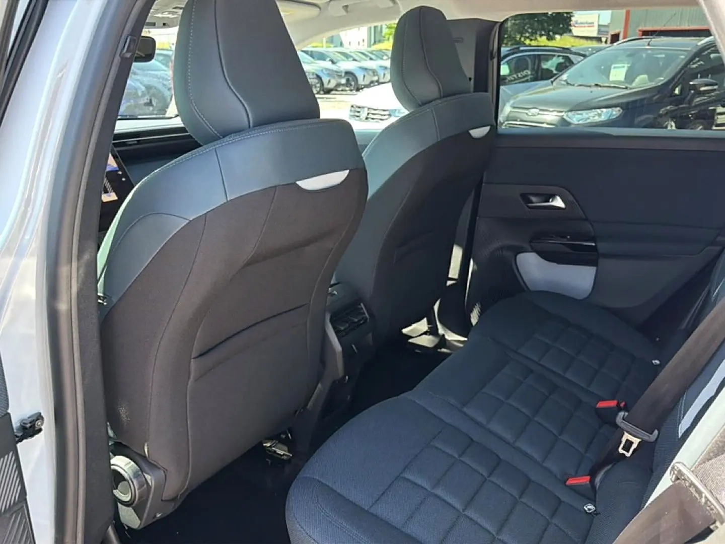 Vue intérieure arrière côté gauche du Citroën C5 Aircross blanc, montrant les sièges arrière et dossiers avant noirs.