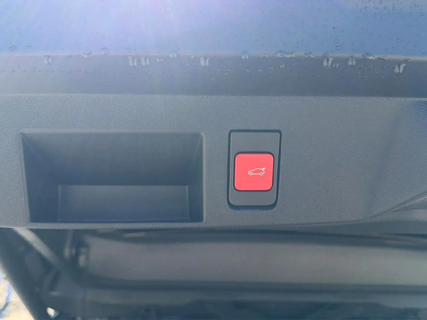 Bouton rouge d'ouverture électrique du hayon visible en gros plan sur le coffre d'un Citroën C5 Aircross blanc et noir.