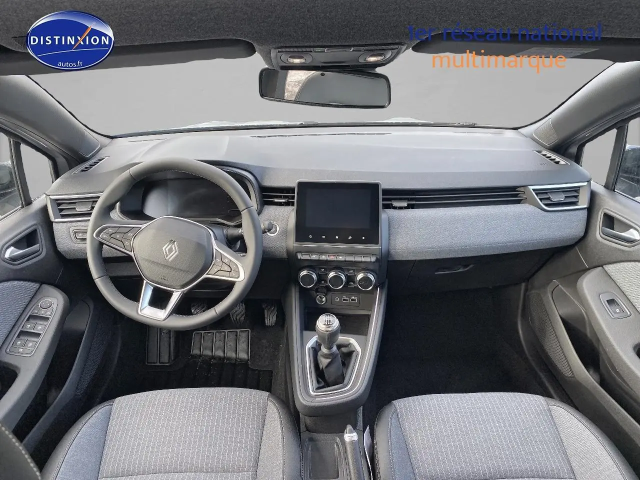 Vue intérieure avant de la Renault Clio V gris rafale, volant multifonction et boîte manuelle au centre.