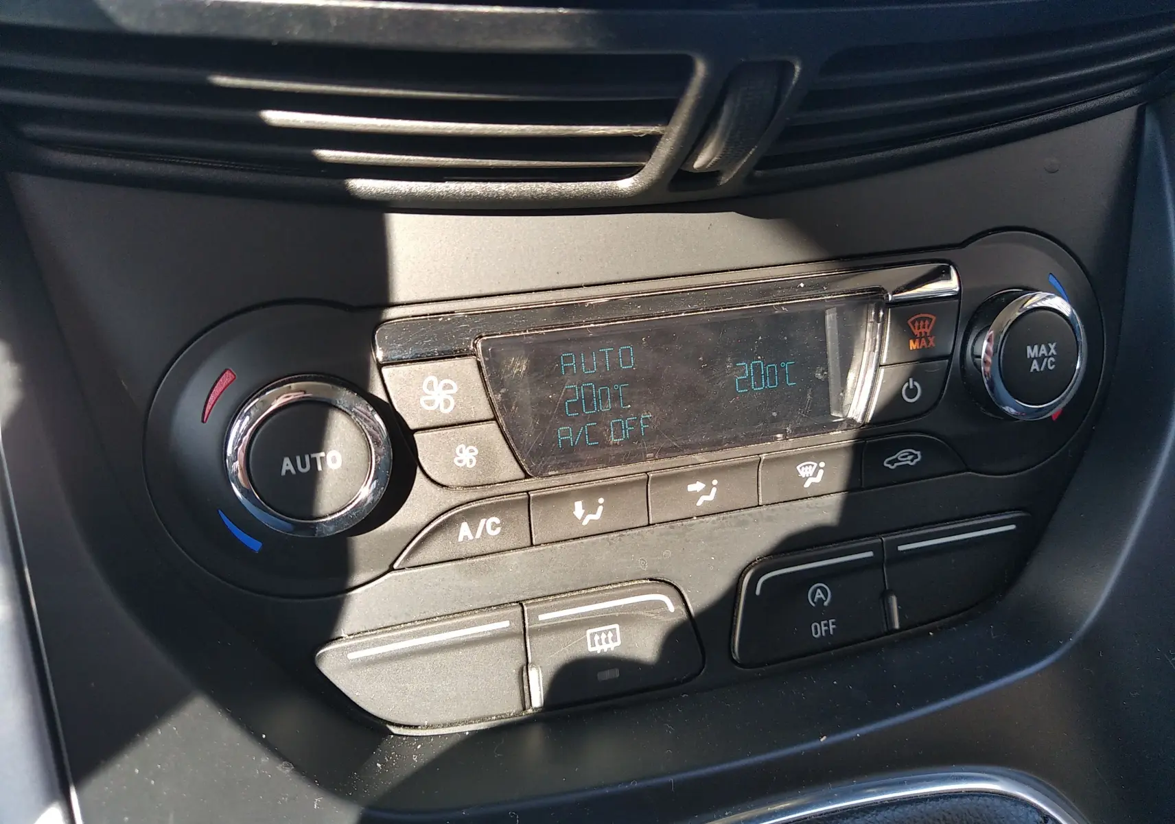 Gros plan sur la console de climatisation automatique du Ford C-MAX blanc, affichant 20°C et commandes tactiles.